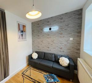 a living room with a black couch and a brick wall at Wembley Park prime location for Stadium events City break in London