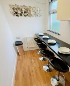 a kitchen with black counter tops and stools at Wembley Park prime location for Stadium events City break in London +1 photo