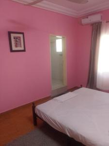 圣路易斯Keur Fall Aéroport appartement f4的一间卧室配有一张床和粉红色的墙壁