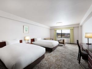 a hotel room with two beds and a desk at Mercure Saga Karatsu Resort in Karatsu +116 photos