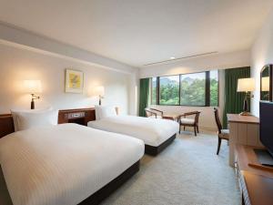 a hotel room with two beds and a television at Mercure Urabandai Resort & Spa in Kitashiobara