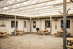 eine Terrasse mit Holztischen und Bänken in einem Gebäude in der Unterkunft Danhostel Thyborøn in Thyborøn