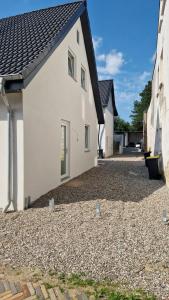 a white house with a gravel driveway at Stadtnah an der Förde 5704 in Flensburg