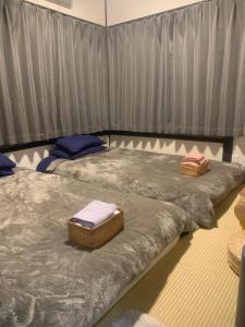 Dos camas en una habitación con sábanas y toallas grises. en 仁信小屋, en Tokio