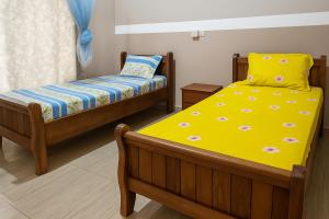 a bedroom with two beds with yellow sheets at Ste Raphaelle Guest House in Yaoundé