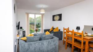 un salon avec un canapé bleu et une table dans l'établissement Greenings Apt Warrington - 2 Bed with FREE off road Parking & Wifi, à Warrington