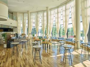 Un restaurante con taburetes y mesas en una sala con grandes ventanales. en Grand Mercure Awaji Island Resort & Spa, en Minamiawaji