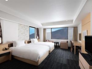 a hotel room with two beds and a flat screen tv at Mercure Miyagi Zao Resort & Spa in Zao