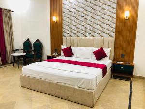 una camera da letto con un letto grande con cuscini rossi e bianchi di Holiday One Hotel & Suites a Karachi