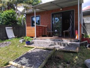 a small house with a porch and a table and chairs at Bungalow des palmistes in Saint-Benoît