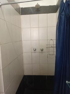 a tiled shower with a blue curtain in a bathroom at Brackendene Lodge in Gaborone +27 photos