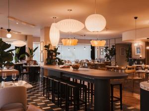 a restaurant with a large bar with chairs and tables at Mercure London Earls Court in London