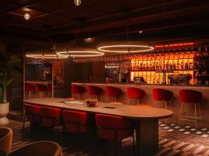 a bar with a wooden table and red chairs at Mercure London Earls Court in London