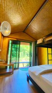 ein Schlafzimmer mit einem Bett und einem großen Fenster in der Unterkunft โฮมสเตย์ เนเจอร์ เดอ สะปัน Nature De Sapan in Ban Huai Ti