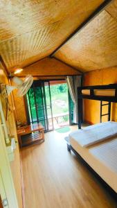 ein Schlafzimmer mit einem Bett und einem großen Fenster in der Unterkunft โฮมสเตย์ เนเจอร์ เดอ สะปัน Nature De Sapan in Ban Huai Ti