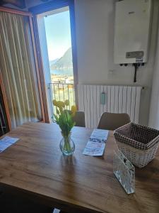 a vase of flowers on a wooden table with a window at MUM & DAD - Loft in Sale Marasino
