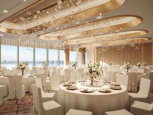 un salón de baile con mesas y sillas blancas y ventanas en Swissôtel Corniche Park Towers Doha, en Doha 57 fotos más