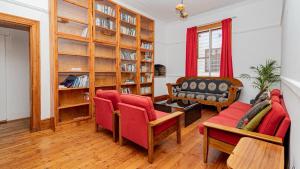 a living room with red furniture and a book shelf at Blossom Boutique Guesthouse in Muizenberg