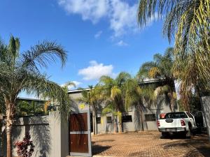 ein Auto, das vor einem Gebäude mit Palmen parkt in der Unterkunft Grand Inn Hotel-Venda in Thohoyandou