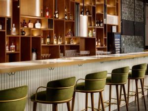 a bar with green chairs in a restaurant at Pullman Zagreb in Zagreb