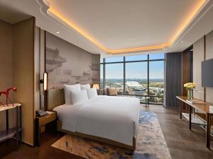 a bedroom with a large white bed and a large window at Pullman Hai Phong Grand Hotel in Hai Phong