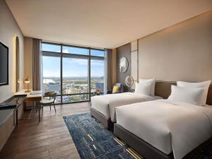 a hotel room with two beds and a large window at Pullman Hai Phong Grand Hotel in Hai Phong