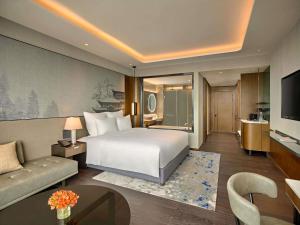 a hotel room with a bed and a living room at Pullman Hai Phong Grand Hotel in Hai Phong