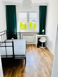 ein Schlafzimmer mit grünen Vorhängen und einem Bett und einem Schreibtisch in der Unterkunft Apartament Sasankowa z bezpłatnym parkingiem in Lyck