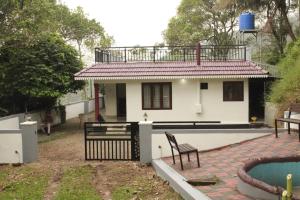 a small white house with a chair in front of it at Valley Homestay in Devikolam +8 photos