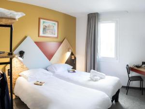 a hotel room with two beds and a window at greet Hôtel Montbéliard in Montbéliard +39 photos