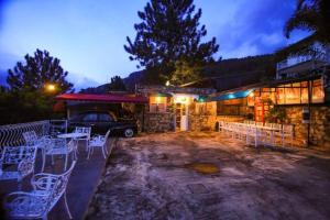 a patio with white chairs and a car parked in front of a building at Skyhill Kandy in Hindagala