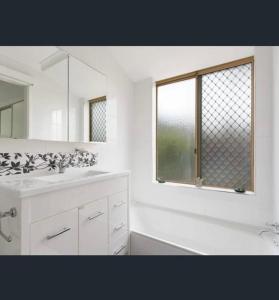 een witte badkamer met een wastafel en een raam bij Perfect home Nice location quiet holiday home with beautiful yard in Perth