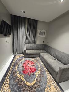 a living room with a couch and a rug with roses at شقق المطار in Jeddah