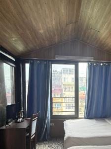 a bedroom with a bed and a desk and a window at Hanoi Hidden Guest House in Hanoi