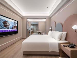 una camera da letto con un grande letto bianco e una TV a schermo piatto di Mercure Hefei South Railway Station a Hefei