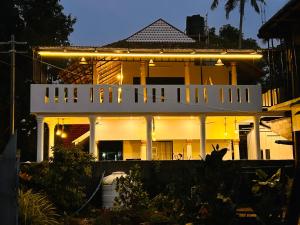 Una gran casa blanca con luces encima. en Marari Beach Cleetus Homestay, en Alleppey