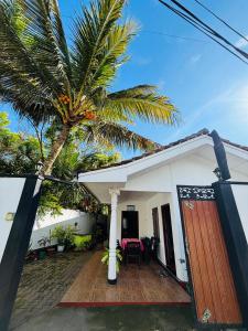 a house with a palm tree in front of it at Uvindu Villa - Cozy By Midigama in Weligama