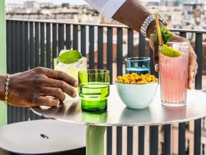 a person holding a tray with two drinks on a table at TRIBE Paris Clichy in Clichy
