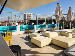 a rooftop patio with chairs and tables and umbrellas at TRIBE Paris Clichy in Clichy