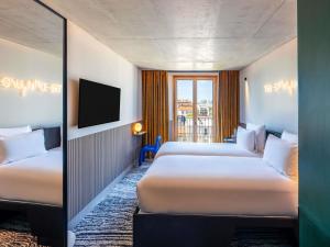 a hotel room with two beds and a television at TRIBE Paris Clichy in Clichy