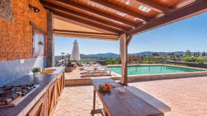 una cocina al aire libre con mesa y piscina en Casa Perdi Riogordo by Ruralidays, en Ríogordo