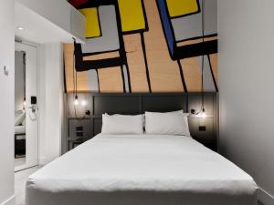 Un dormitorio con una cama con una pintura encima. en Hotel Woolstore 1888, Sydney - Handwritten Collection, en Sídney