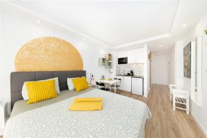 1 dormitorio blanco con 1 cama grande con almohadas amarillas en Apart hotel Ponderosa with a pool & view, studio 226, en Playa Fañabe