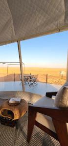 a living room with a table and a view of the desert at Starry Domes Desert Camp in Bidiyah