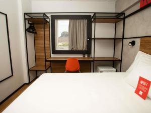 a bedroom with a bed and a window and a orange chair at Ibis Serra Talhada in Serra Talhada +56 photos