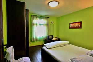 zieloną sypialnię z łóżkiem i oknem w obiekcie Private 4BR-2BA guest House Dryanovo with Pool and FREE Parking w mieście Drjanowo