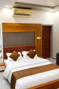 Un dormitorio con una cama grande con sábanas blancas y almohadas marrones. en JD Bro Inn, en Sheoganj