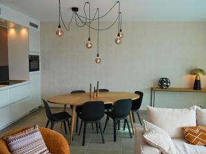 une cuisine et une salle à manger avec une table et des chaises en bois dans l'établissement Appartement moderne 2 chambres & 2 parking à Koksijde by La Conciergerie, à Coxyde