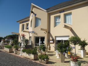 un bâtiment avec des plantes en pot devant lui dans l'établissement Hôtel Le Colombier, à Saint-Pantaléon-de-Larche