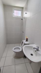 a white bathroom with a toilet and a sink at AL Homestay with 3 Bedrooms in Alor Setar